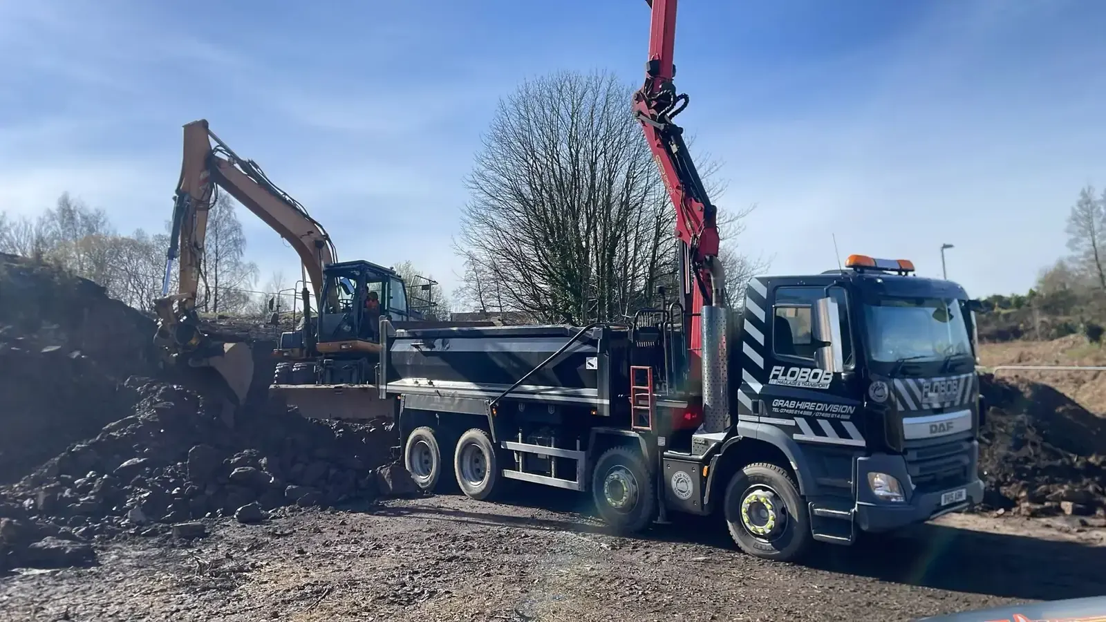 Grab truck working alongside an excavator on a construction site
